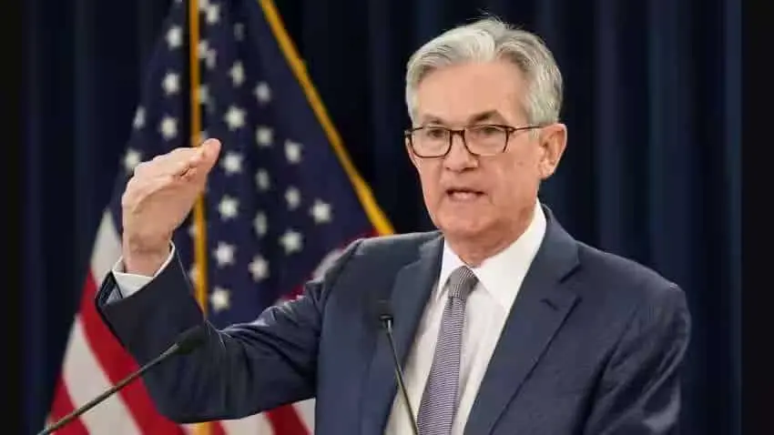 Jerome Powell speaking at a Federal Reserve meeting with flags in the background.