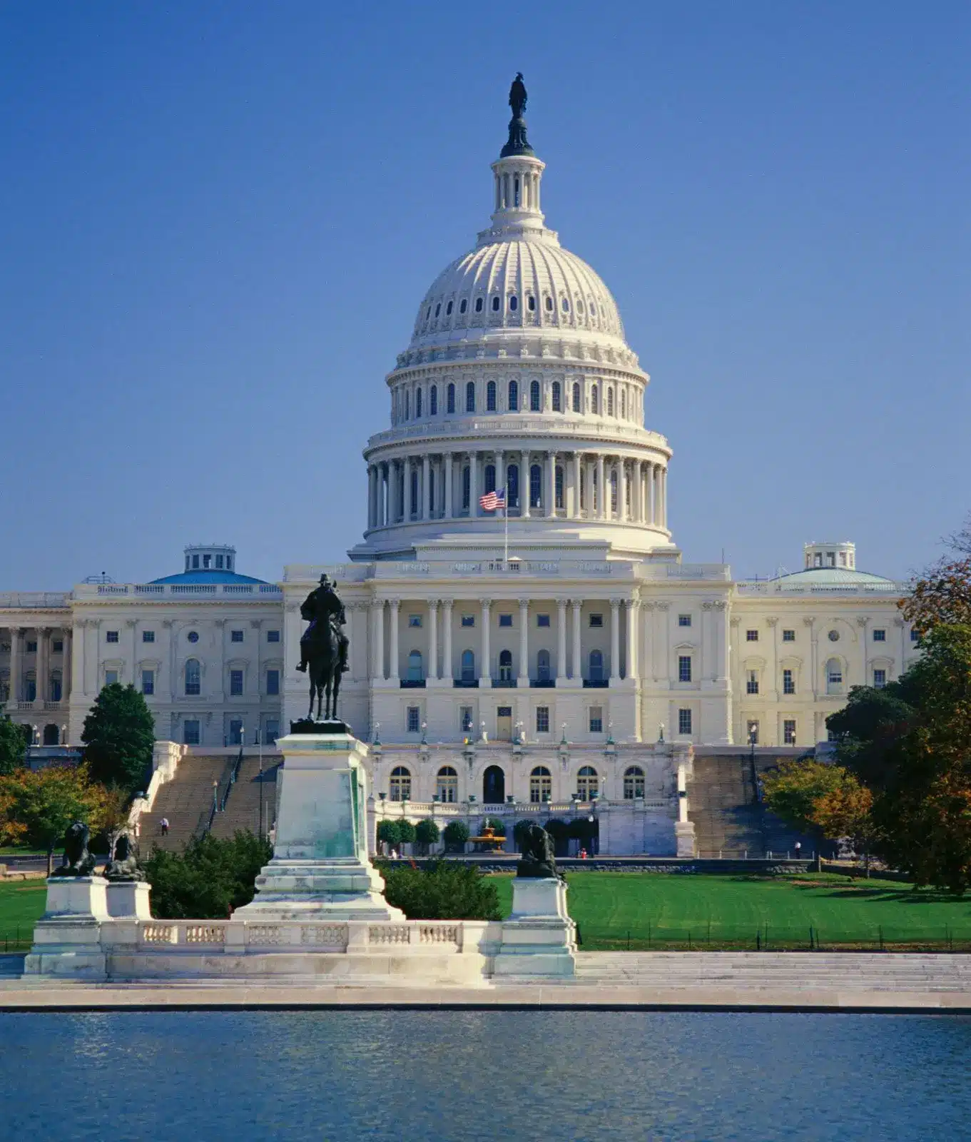 The US Capitol building with clear blue skies and a reflecting pool.