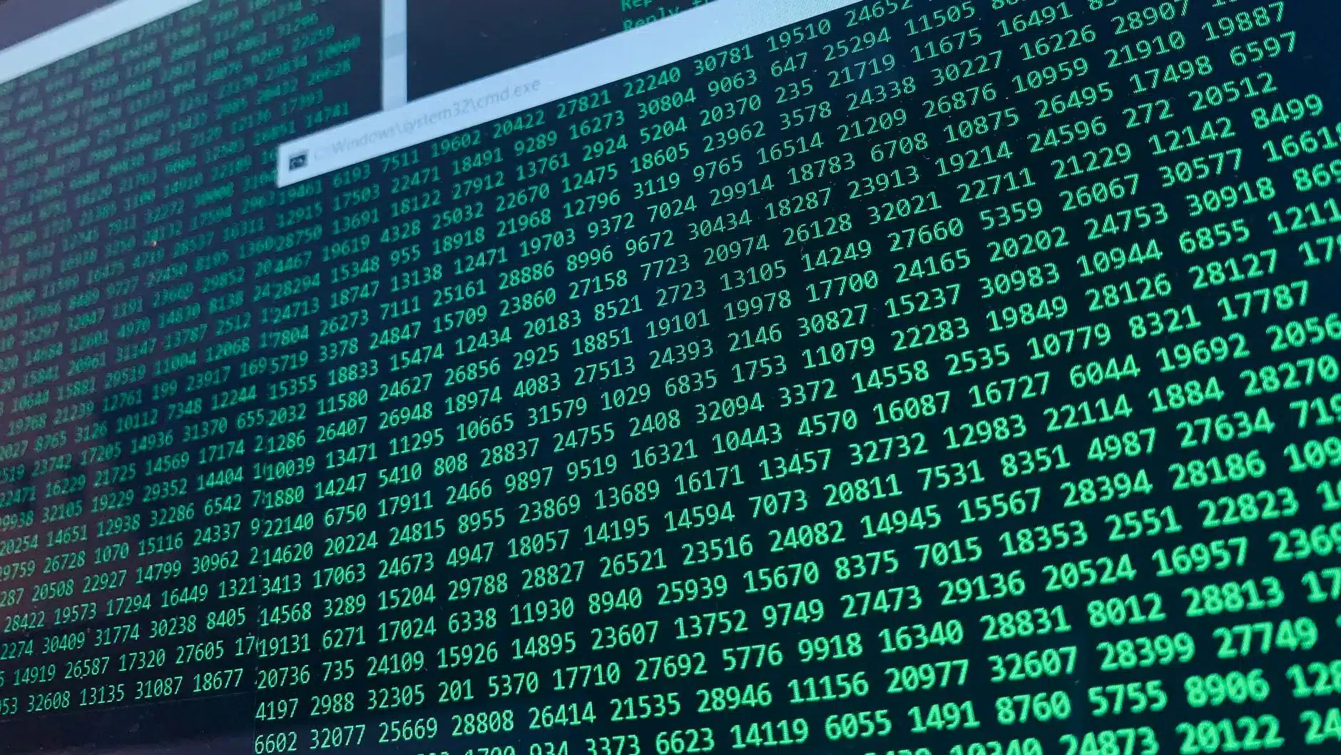 Close-up of a computer screen displaying lines of green code and a Windows command prompt path