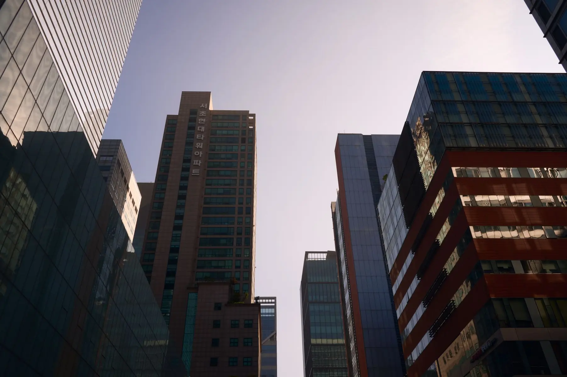 Low-angle view of modern glass skyscrapers in Seoul's financial district under a clear sky.