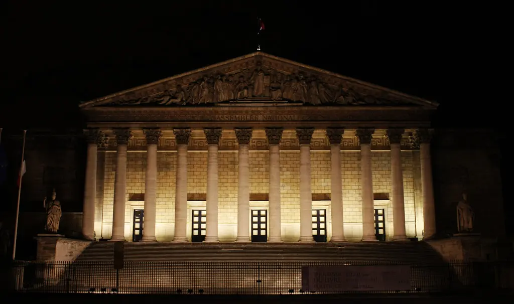 Das beleuchtete Gebäude der Assemblée nationale in Paris bei Nacht.