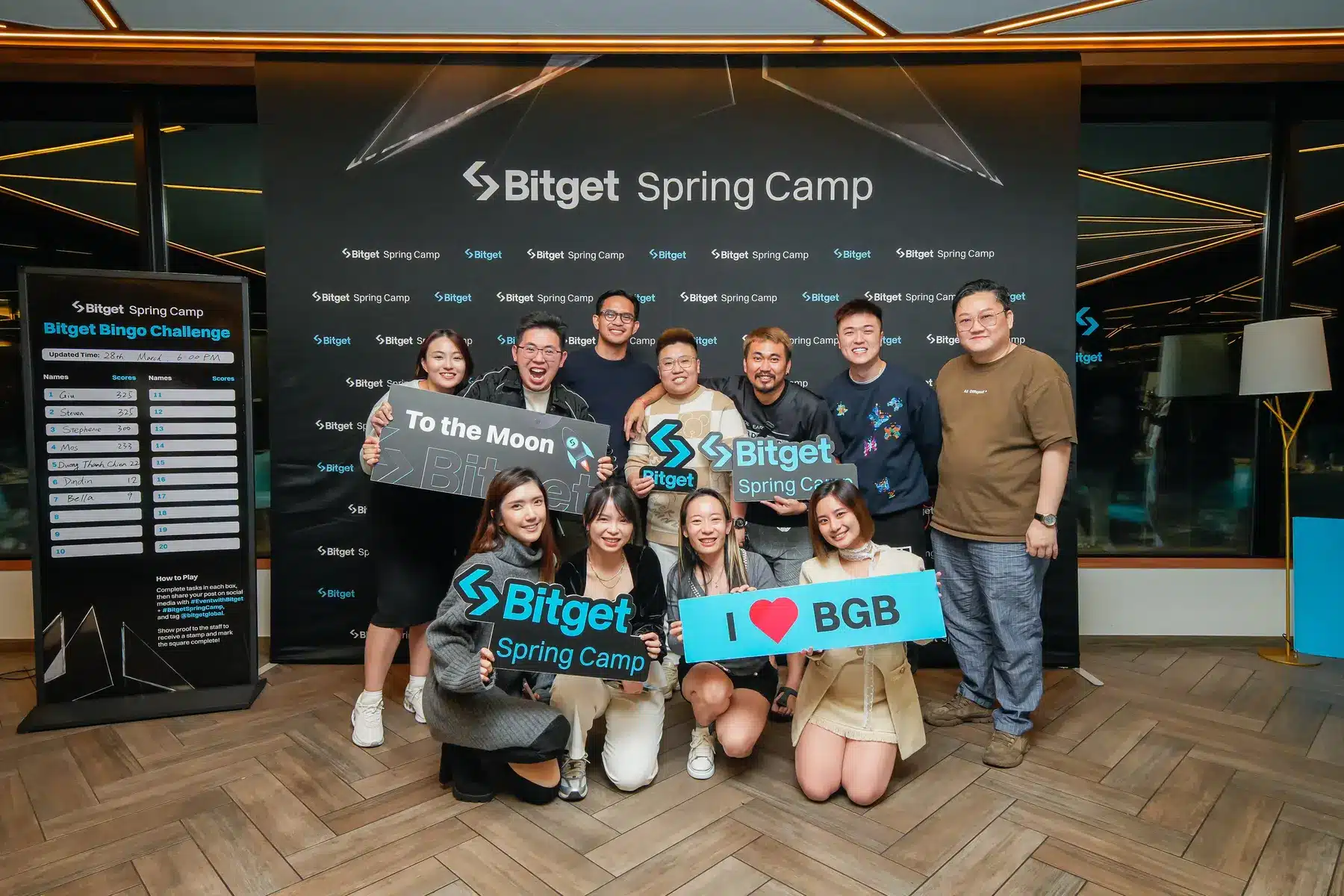Eine Gruppe von Menschen bei einem Bitget Spring Camp Event vor einer Logo-Wand.