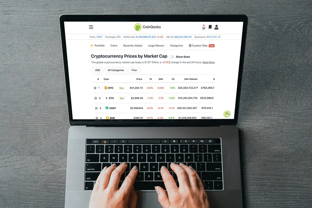 Die CoinGecko-Webseite mit einer Liste von Kryptowährungen nach Marktkapitalisierung auf einem Laptop-Bildschirm.