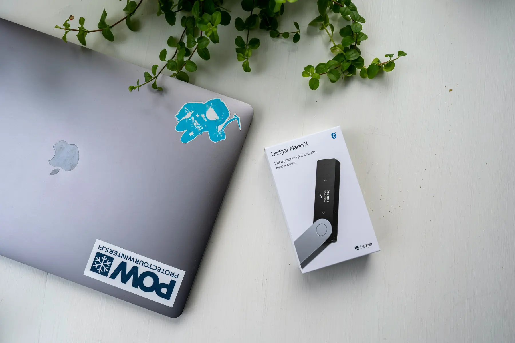Eine Verpackung eines Ledger Nano X Hardware-Wallets neben einem geschlossenen Laptop.