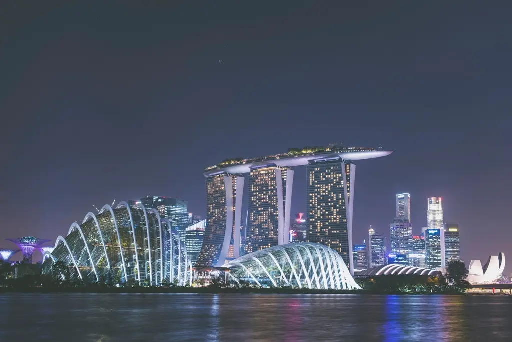 Die beleuchtete Skyline von Singapur bei Nacht mit dem Marina Bay Sands und den Gardens by the Bay.