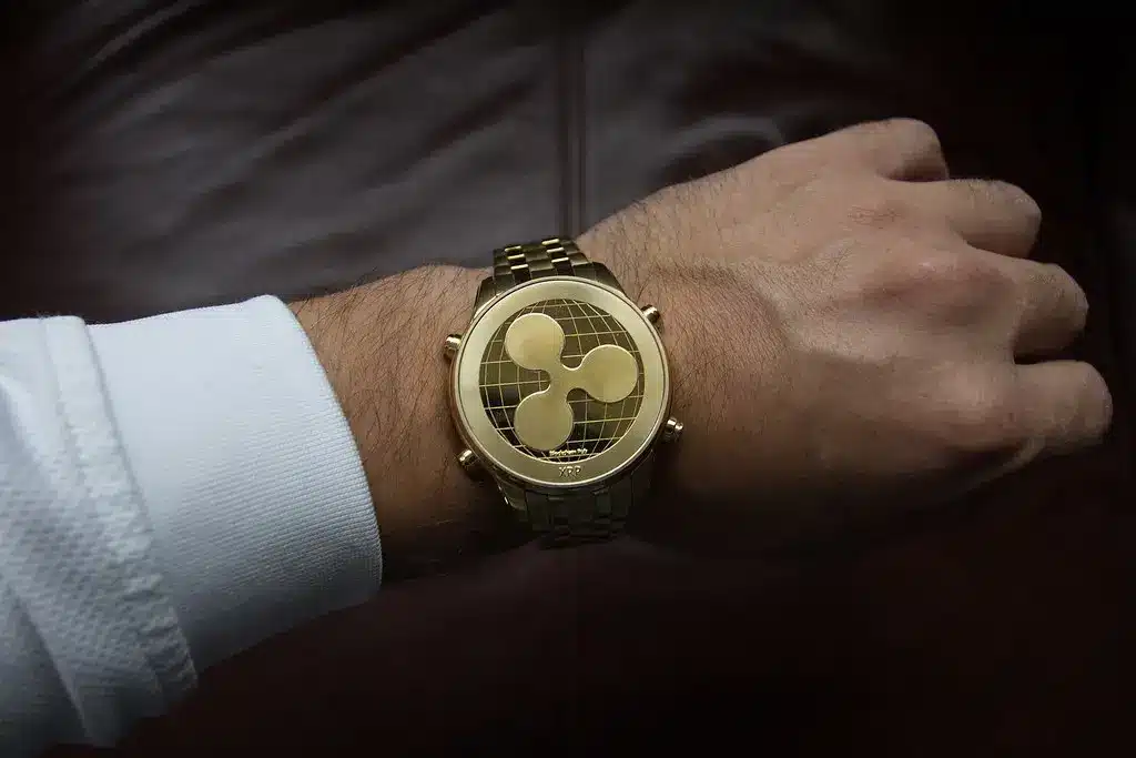 Eine goldene Münze mit dem XRP-Logo, die wie eine Armbanduhr an einem Handgelenk getragen wird.