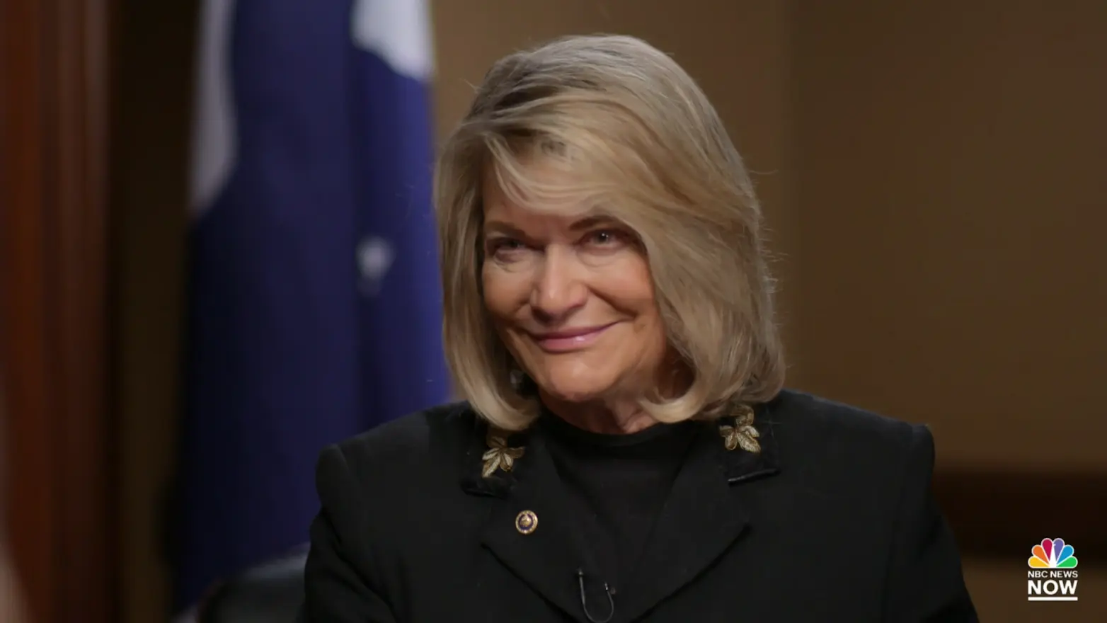 Close-up of a woman with blonde hair smiling during an interview setting.
