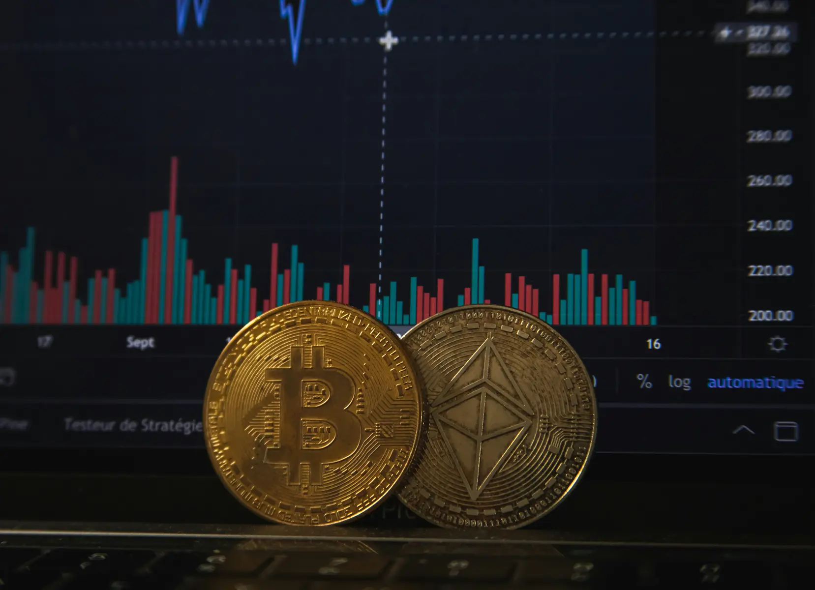 Bitcoin- en Ethereum-munten voor een beeldscherm met cryptomarktgrafieken.