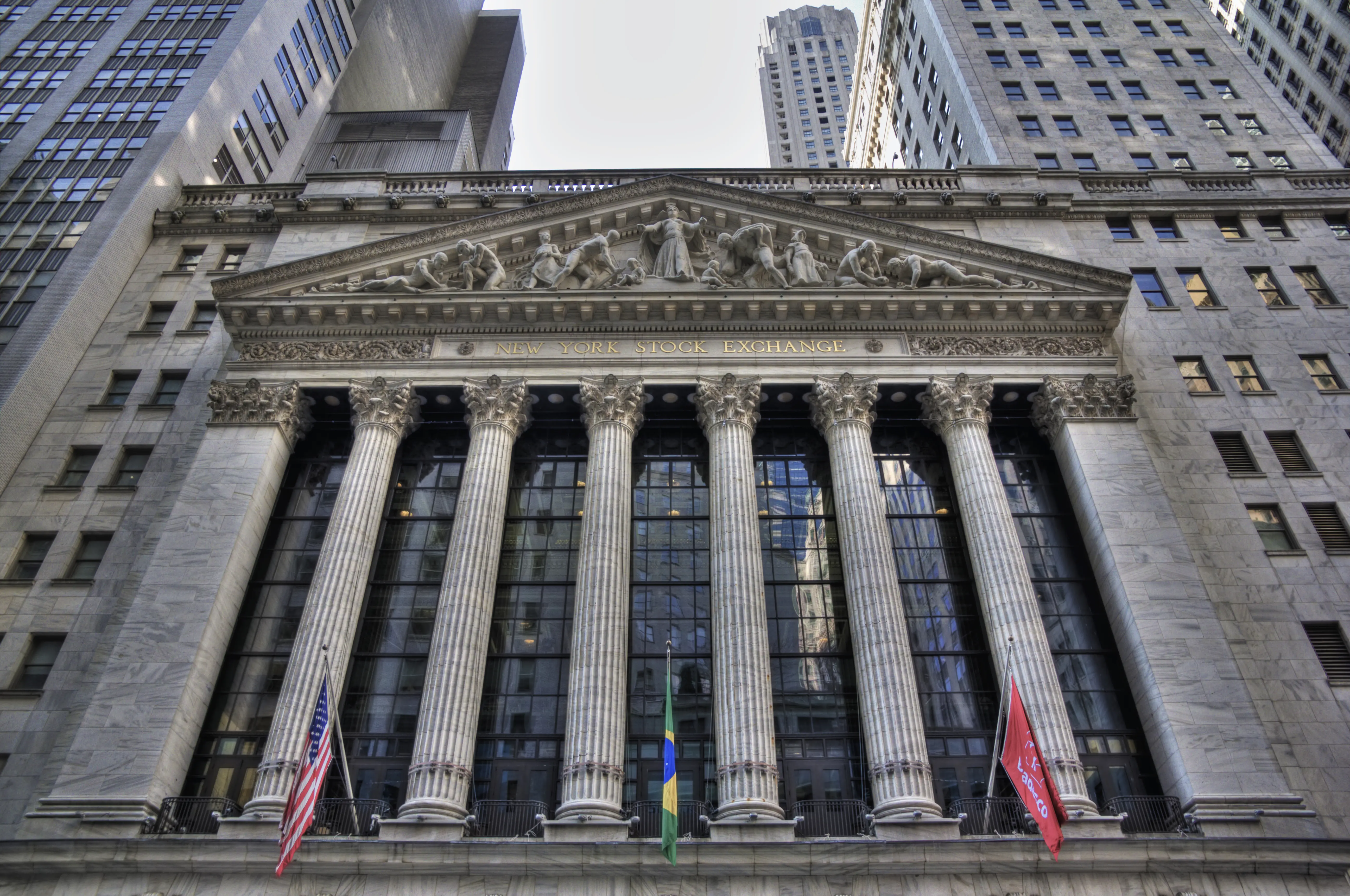 Exterior view of the New York Stock Exchange featuring columns and flags.
