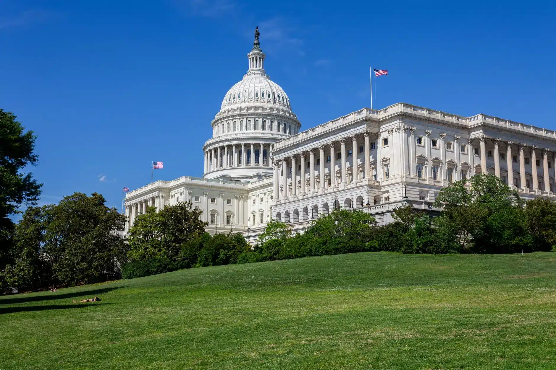 Exterior view of the United States Capitol building with green grass and blue sky.