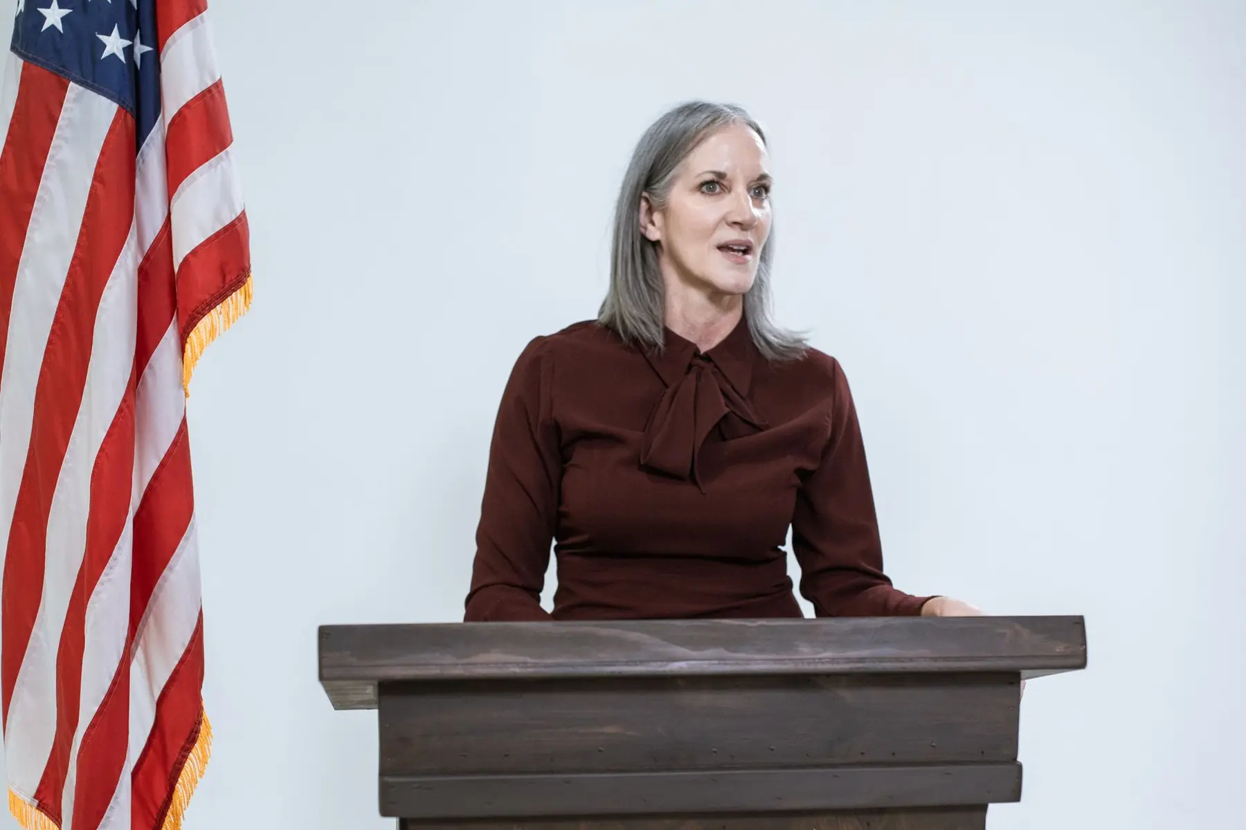 Senator Cynthia Lummis speaking from a wooden podium next to an American flag.